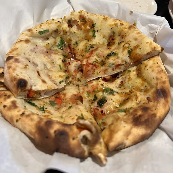 Close-up of Royal Everest's Indian garlic naan bread, topped with herbs and spices, served in a basket.