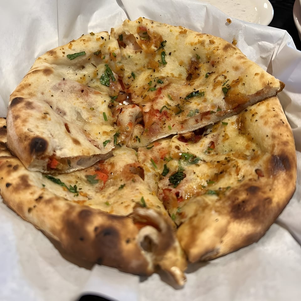 Close-up of Royal Everest's Indian garlic naan bread, topped with herbs and spices, served in a basket.