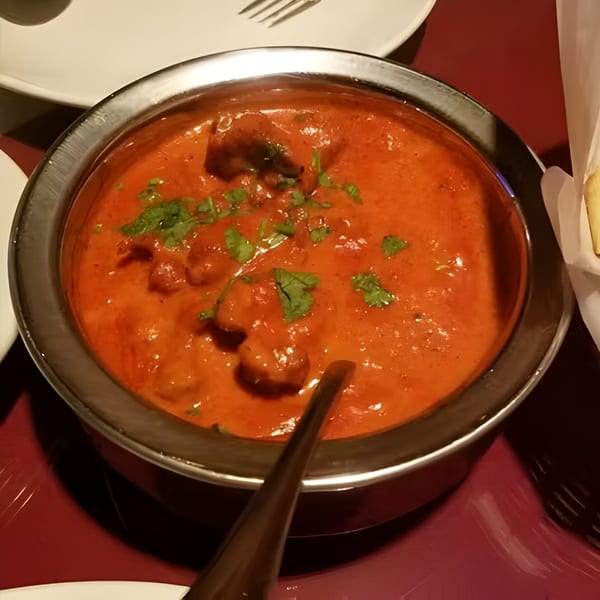 Royal Everest's Indian butter chicken, garnished with fresh cilantro, in a metal serving bowl.